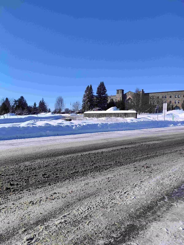 Hauts bancs de neige le long d'une route dégagée, sous un ciel bleu d'hiver