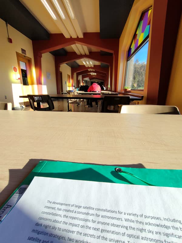 Salle d'étude aux vitraux colorés, vue depuis une table de travail