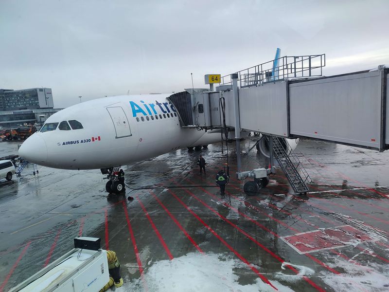 Airbus A330 d'Air Transat à la passerelle, sur un tarmac enneigé